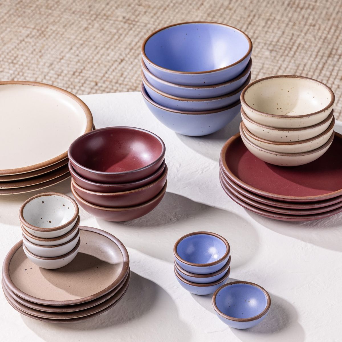 Various stacks of 4 bowls and 4 plates of various shapes on a white table