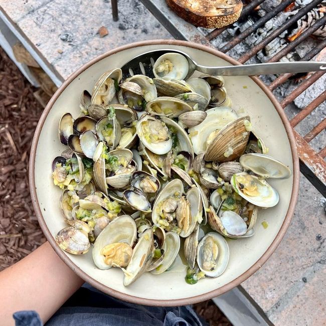 Outside, a hand holds a ceramic coupe plate filled with mussels