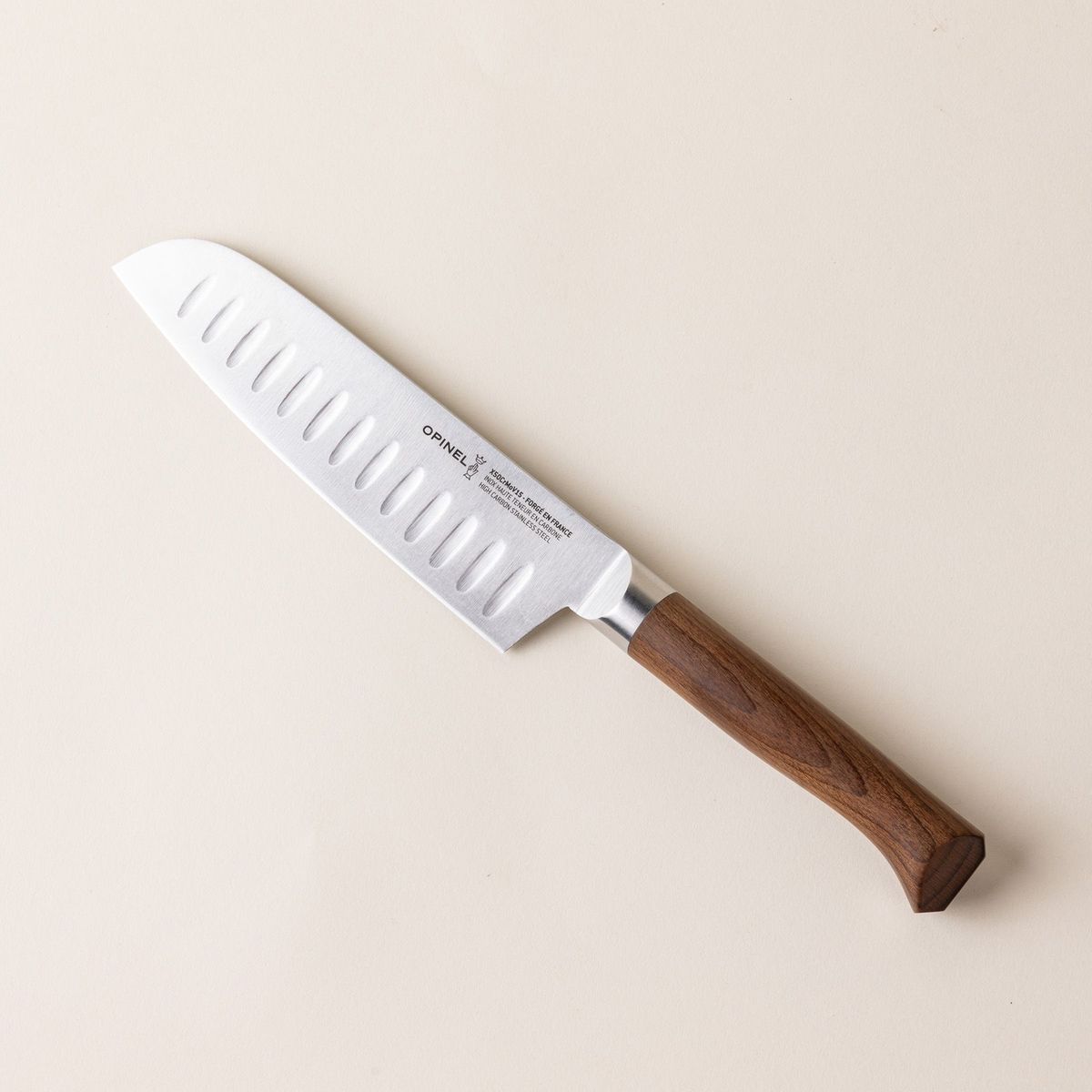 A santoku knife with a sharp steel blade with dimples and a beveled dark wood handle