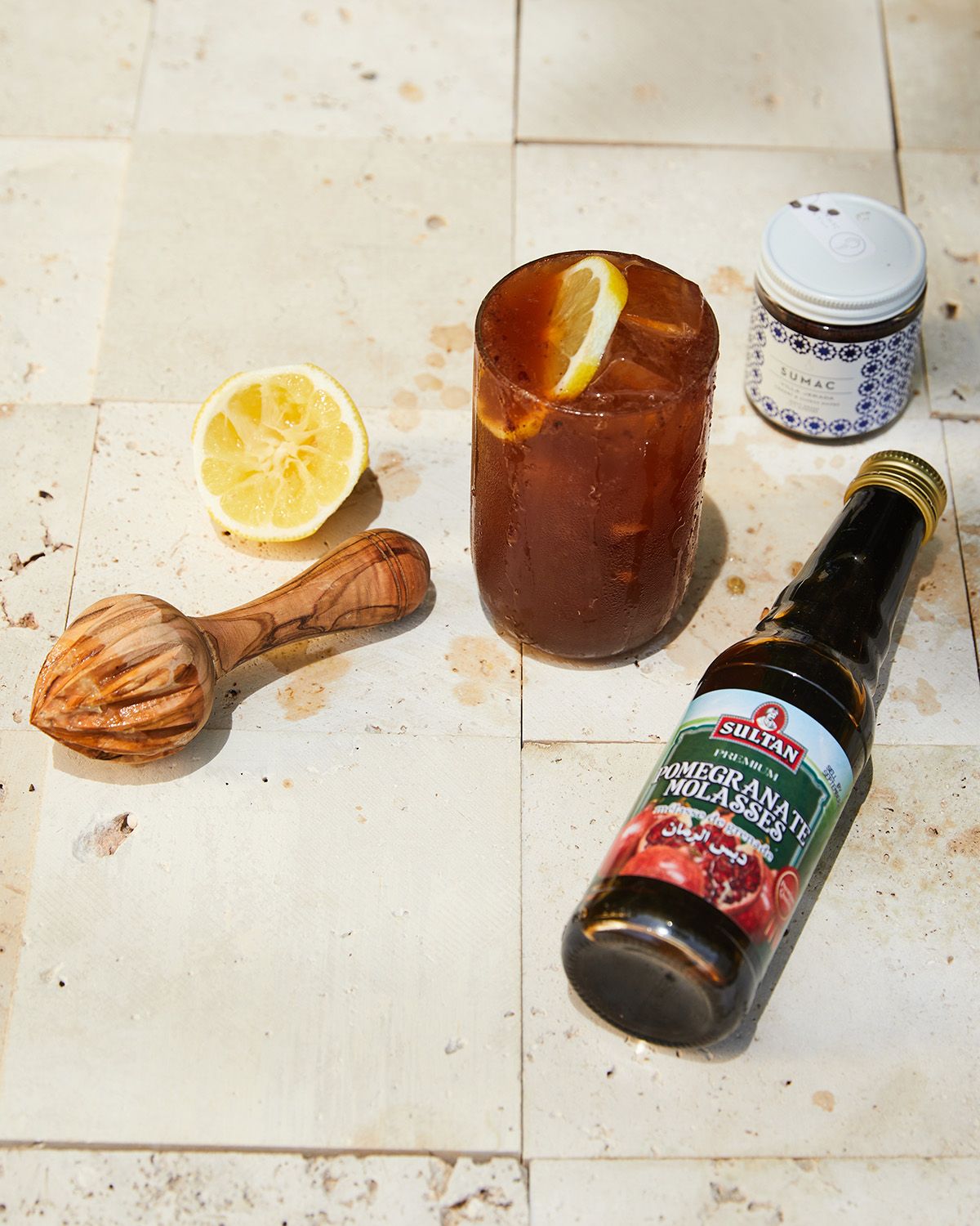 citrus reamer, lemon, cocktail in brown glass, spices and pomegranate molasses