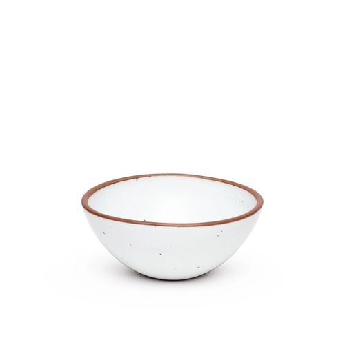 A medium rounded ceramic bowl in a cool white color featuring iron speckles and an unglazed rim