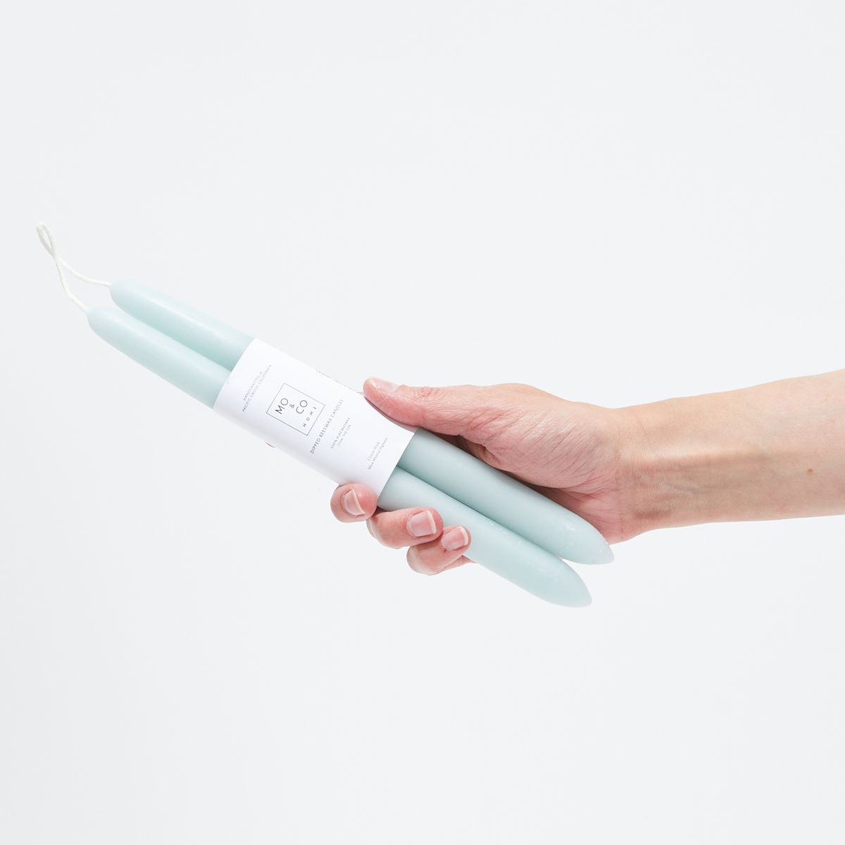 hand holding powder blue taper candles with white label