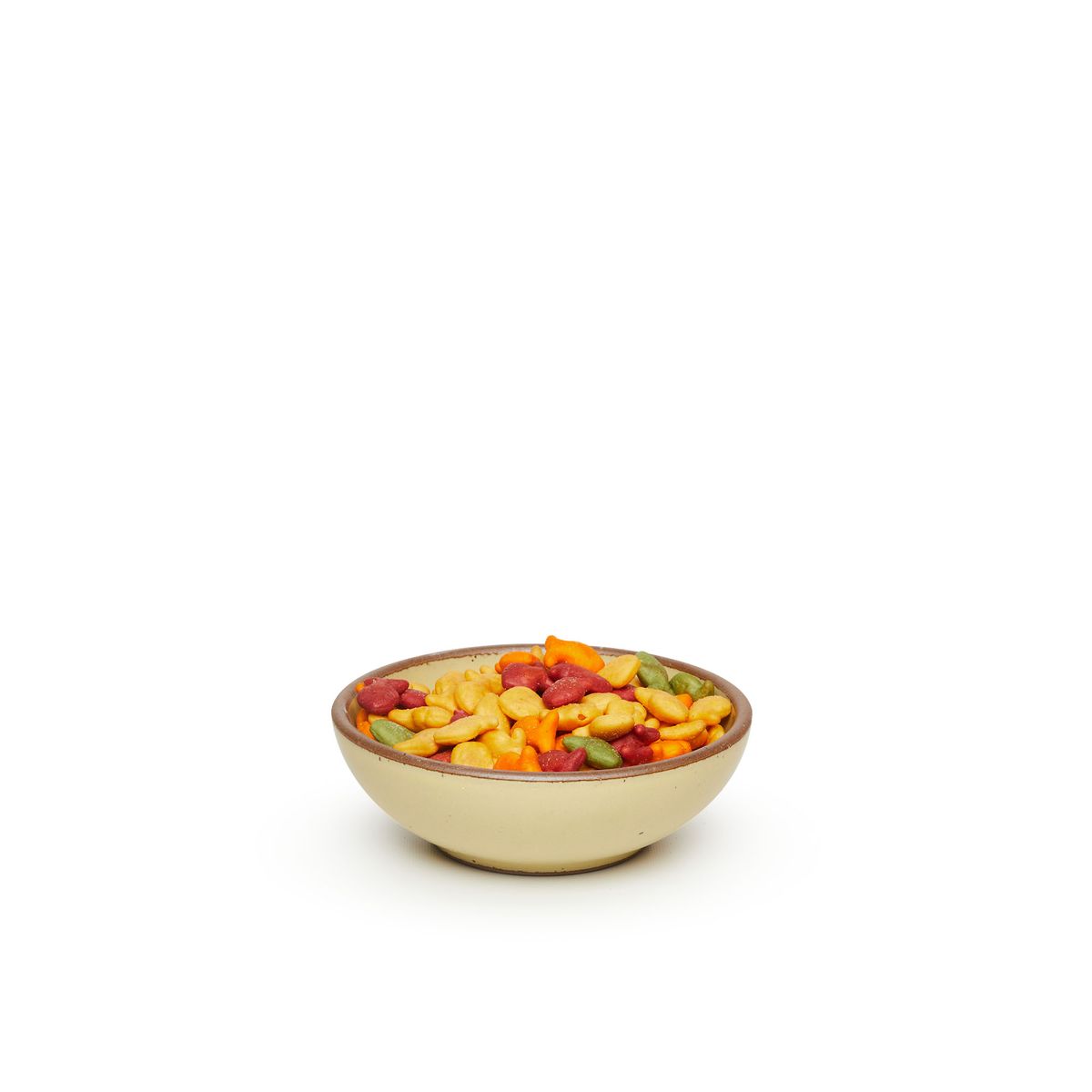 A small shallow ceramic bowl in a light butter yellow color featuring iron speckles and an unglazed rim, filled with colorful crackers