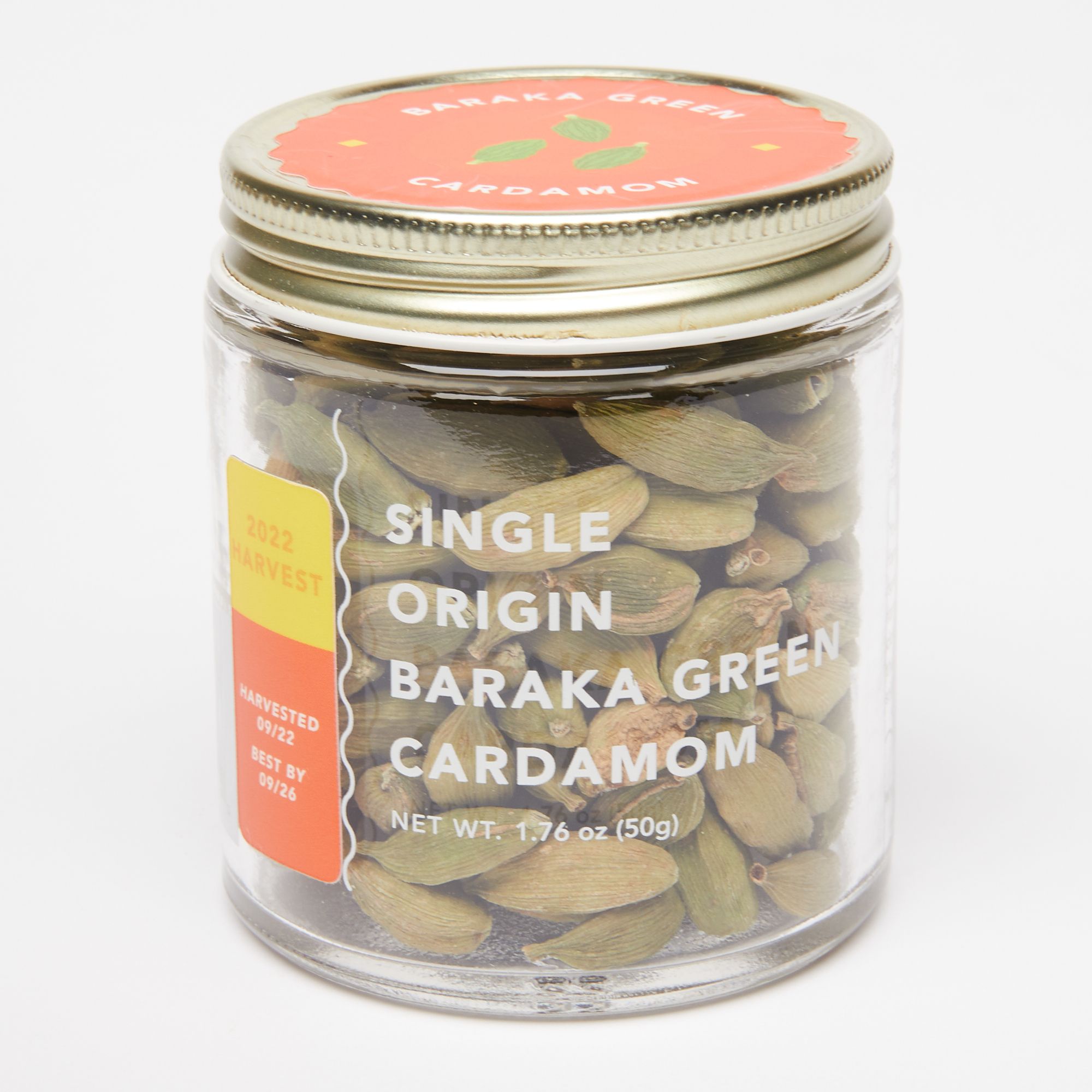 Glass jar filled with cardamom and a transparent label that reads "Single Origin Baraka Green Cardamom"