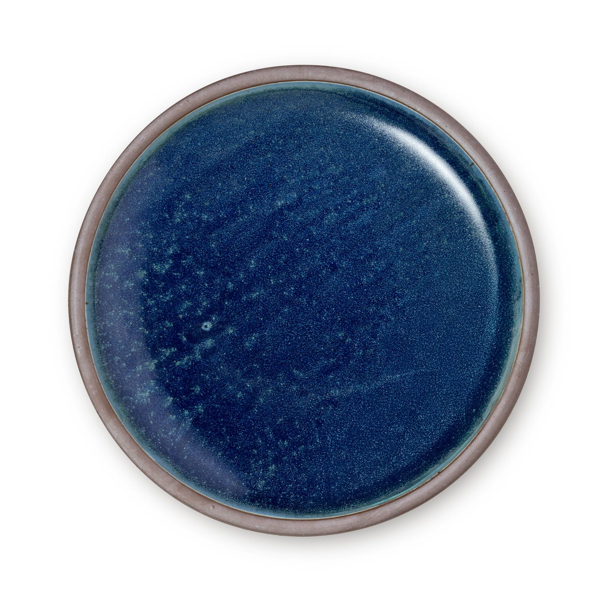 A large ceramic platter in a reflective dappled deep blue color and an unglazed rim.