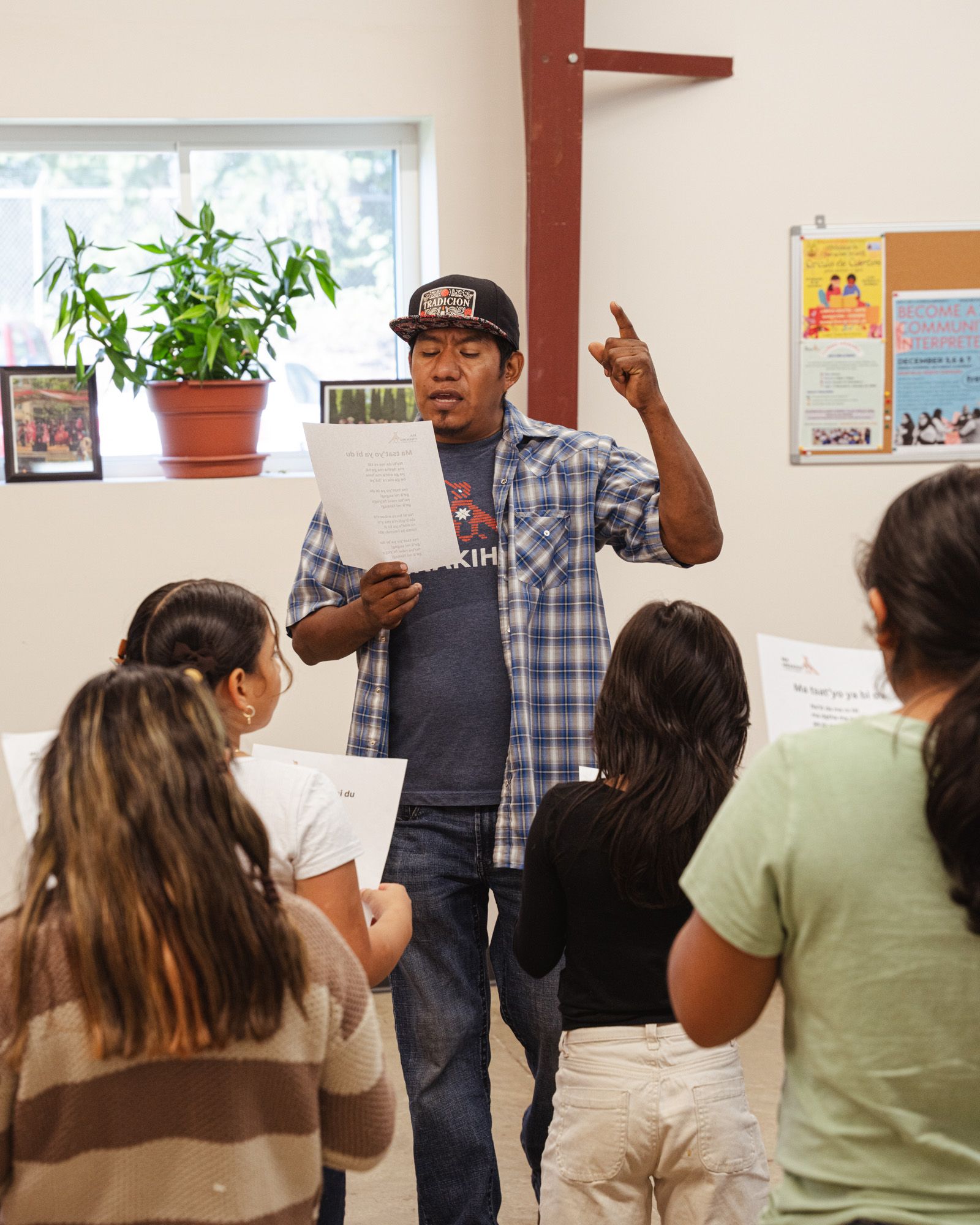 A man standing in front of a group of children singing during a choir practice.
