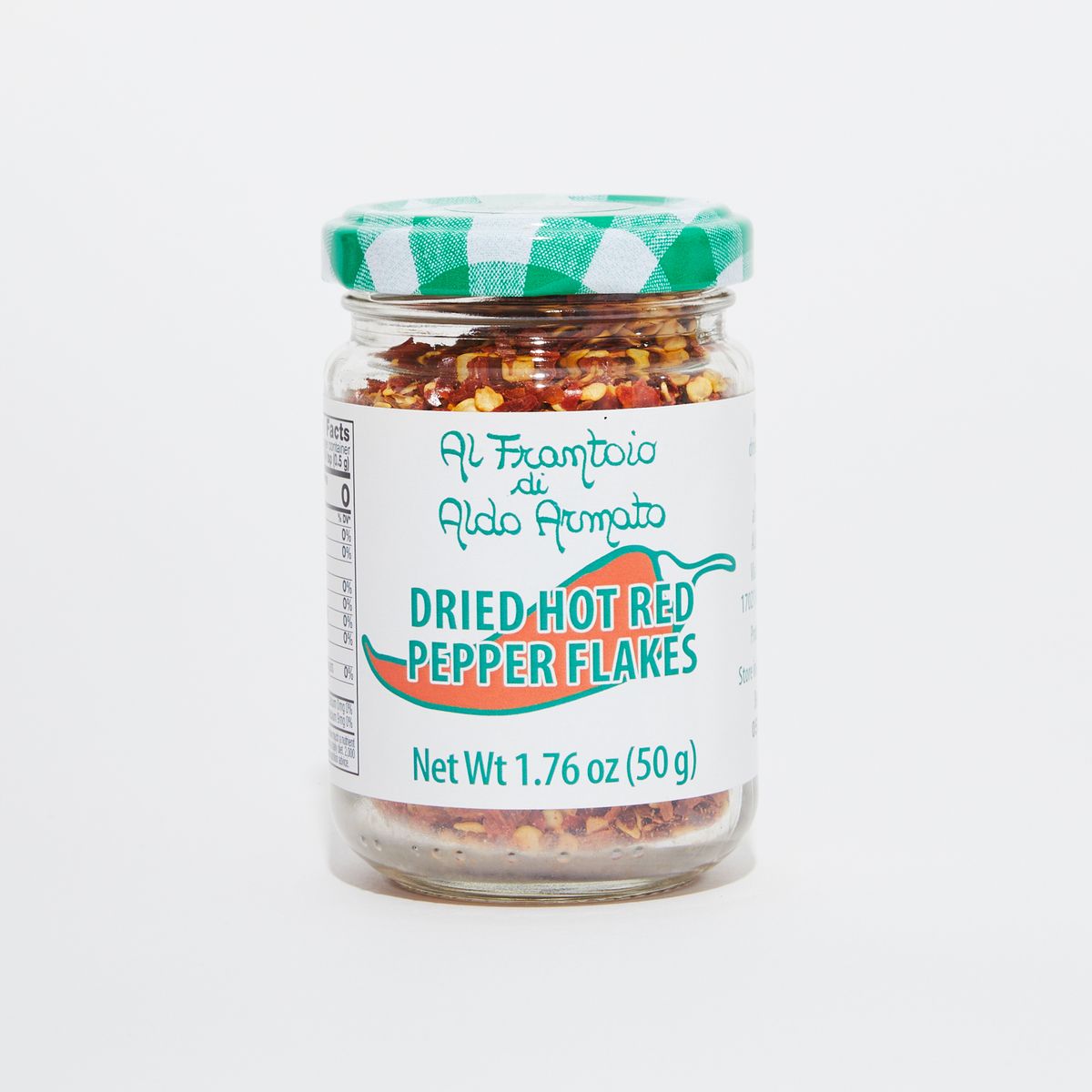 Clear glass jar full of red pepper flakes with a green and white gingham lid and a white label that reads "Dried Hot Red Pepper Flakes" in green lettering