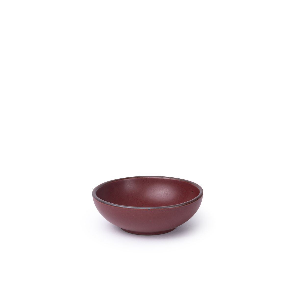 A small shallow ceramic bowl in a plum color featuring iron speckles and an unglazed rim