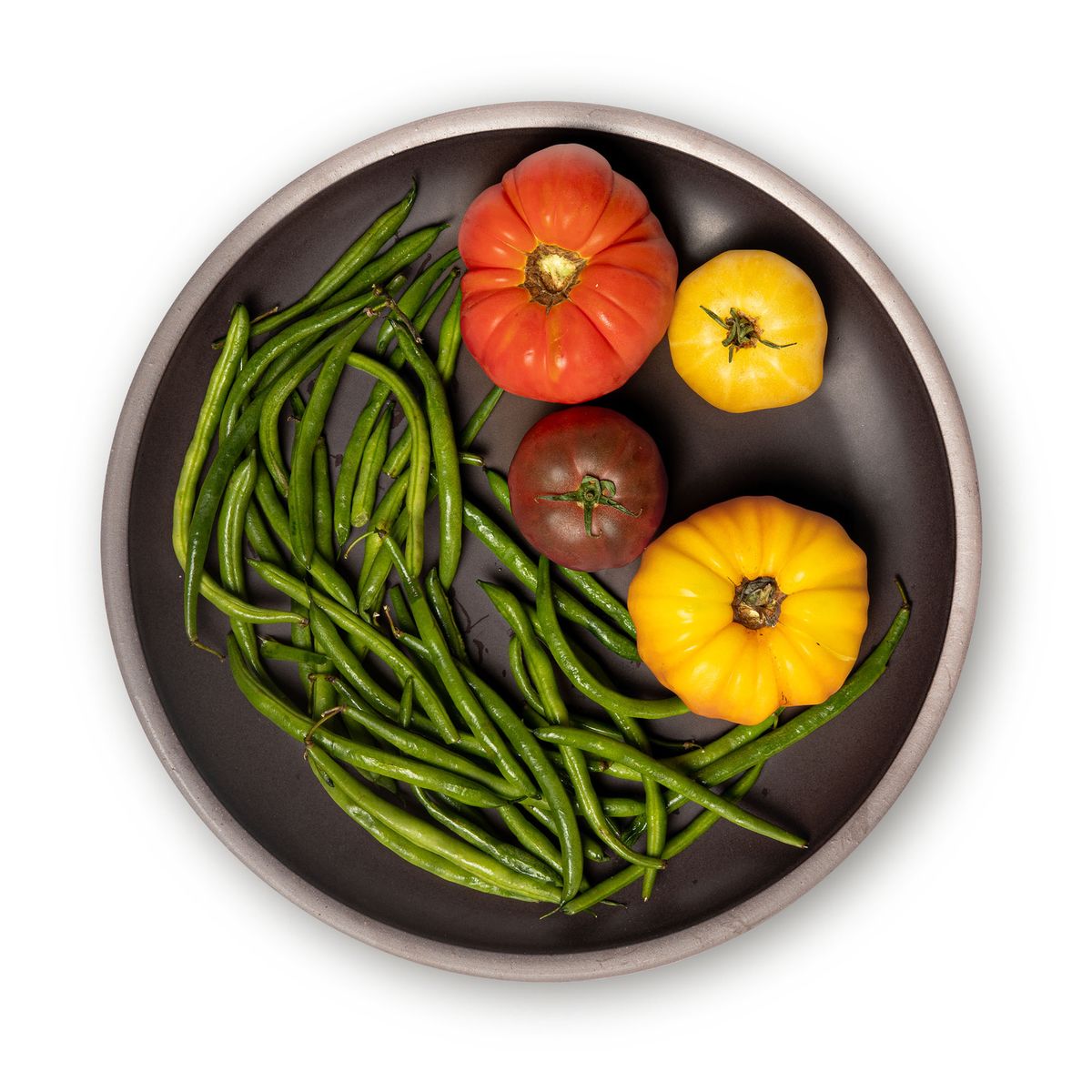 Vegetables on a large ceramic platter in a dark cool brown color featuring iron speckles and an unglazed rim