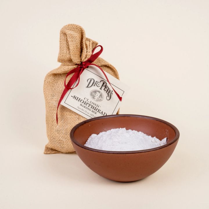 A burlap bag with a red ribbon and a label that reads "Dr. Pete's Shortbread Mix' and a bowl filled with baking mix