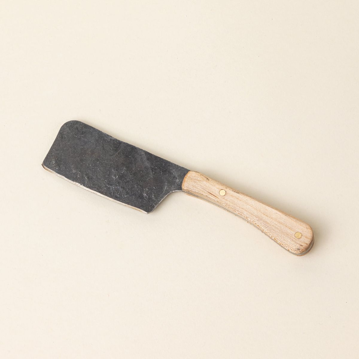 A hand-forged cheese knife with a stainless steel rectangular blade and a maple wood handle