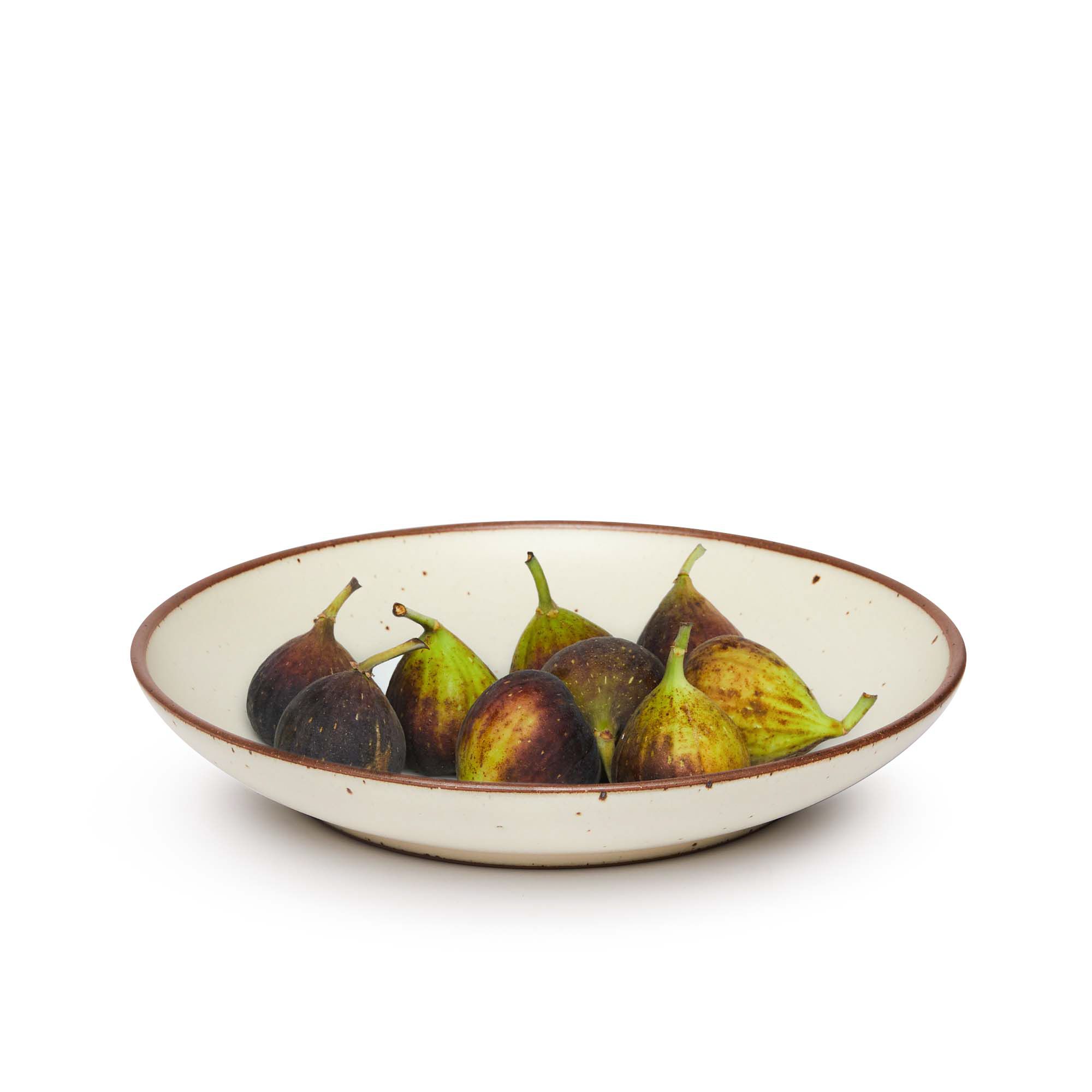 Figs on a large ceramic plate with a curved bowl edge in a warm, tan-toned, off-white color featuring iron speckles and an unglazed rim.