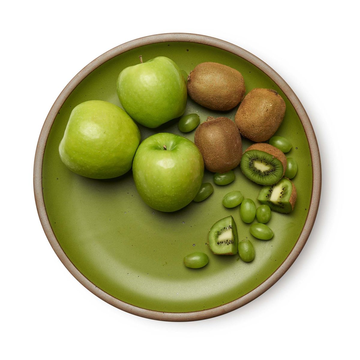 The Serving Platter in Fiddlehead, a mossy, olive green. Pictured here with an array of fruit: three granny smith apples, kiwis, and green grapes, with plenty of room for more fruits to be added.