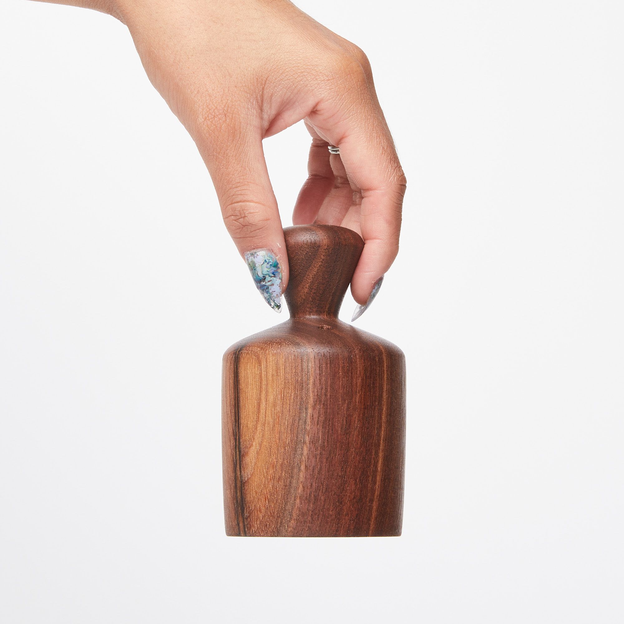 Hand holding the turned knob at the top of a cylindrical black walnut biscuit cutter