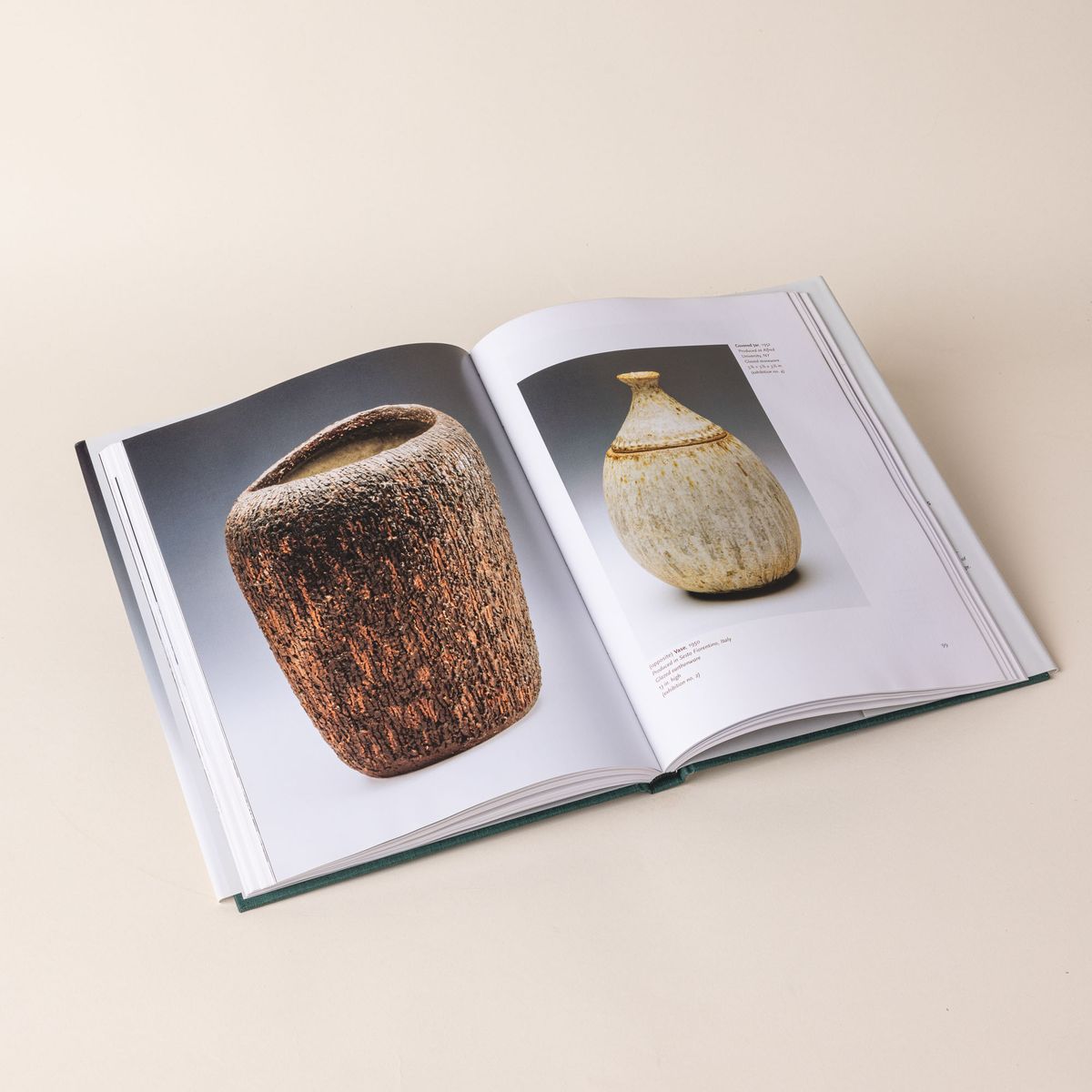 An open hardcover book featuring two different photos of ceramic pottery vases.