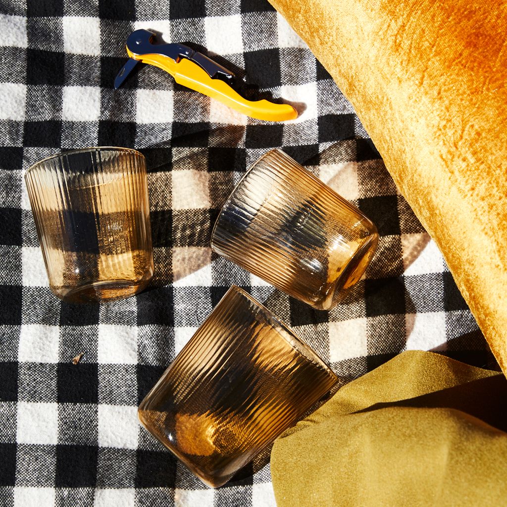Three pale yellow drinking glasses on a black and white checked background