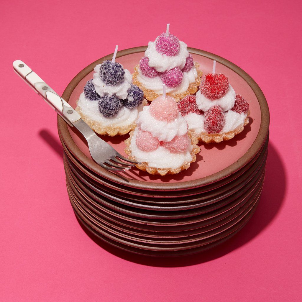 A quartet of candles inspired by fruit tarts sit on a stack of East Fork plates in Rococo.