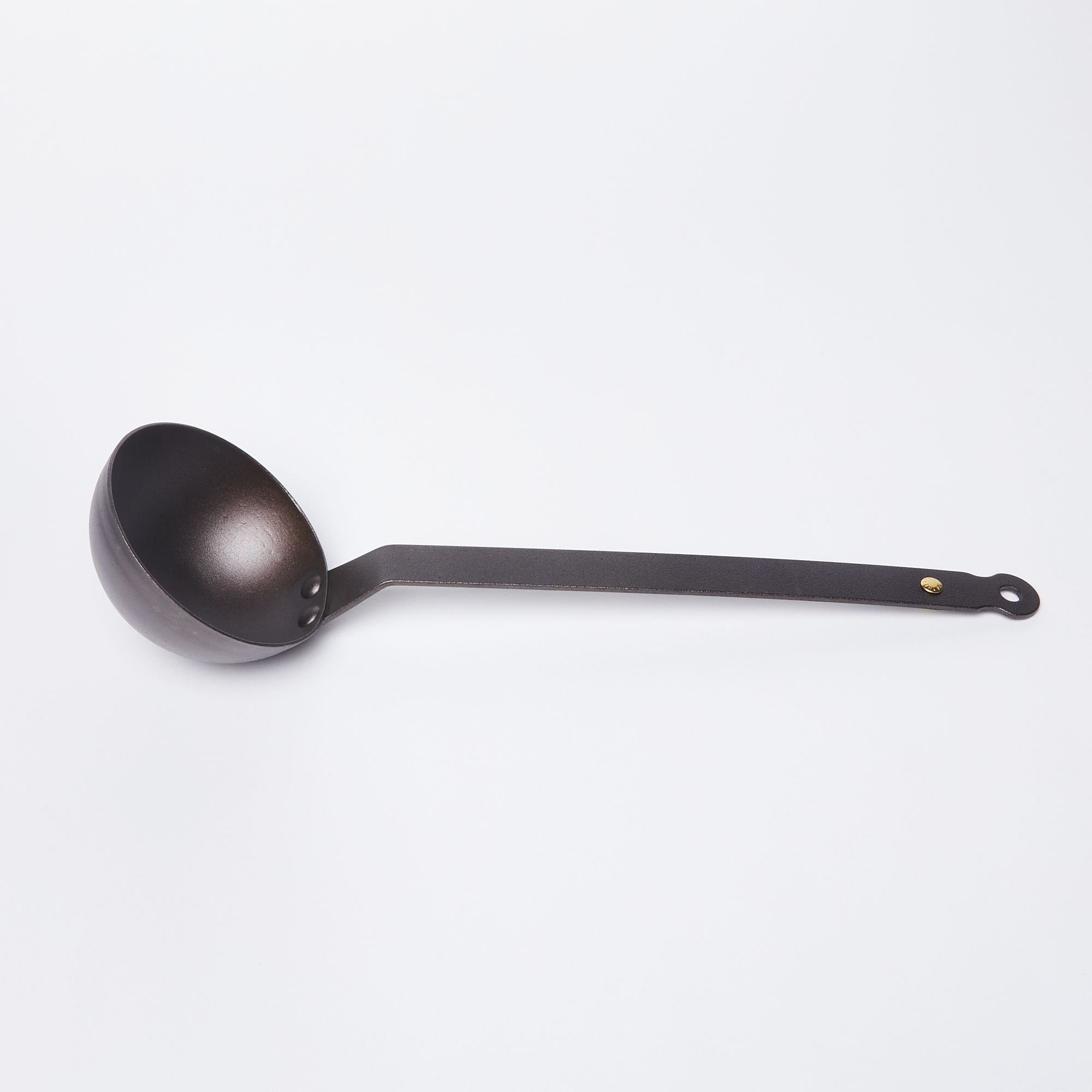 Black metal ladle with cup on the left and a hole at the top of the handle