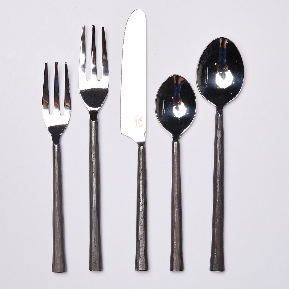 Small fork, large fork, knife, small spoon, large spoon, all with shiny tops and matte black rustic handles
