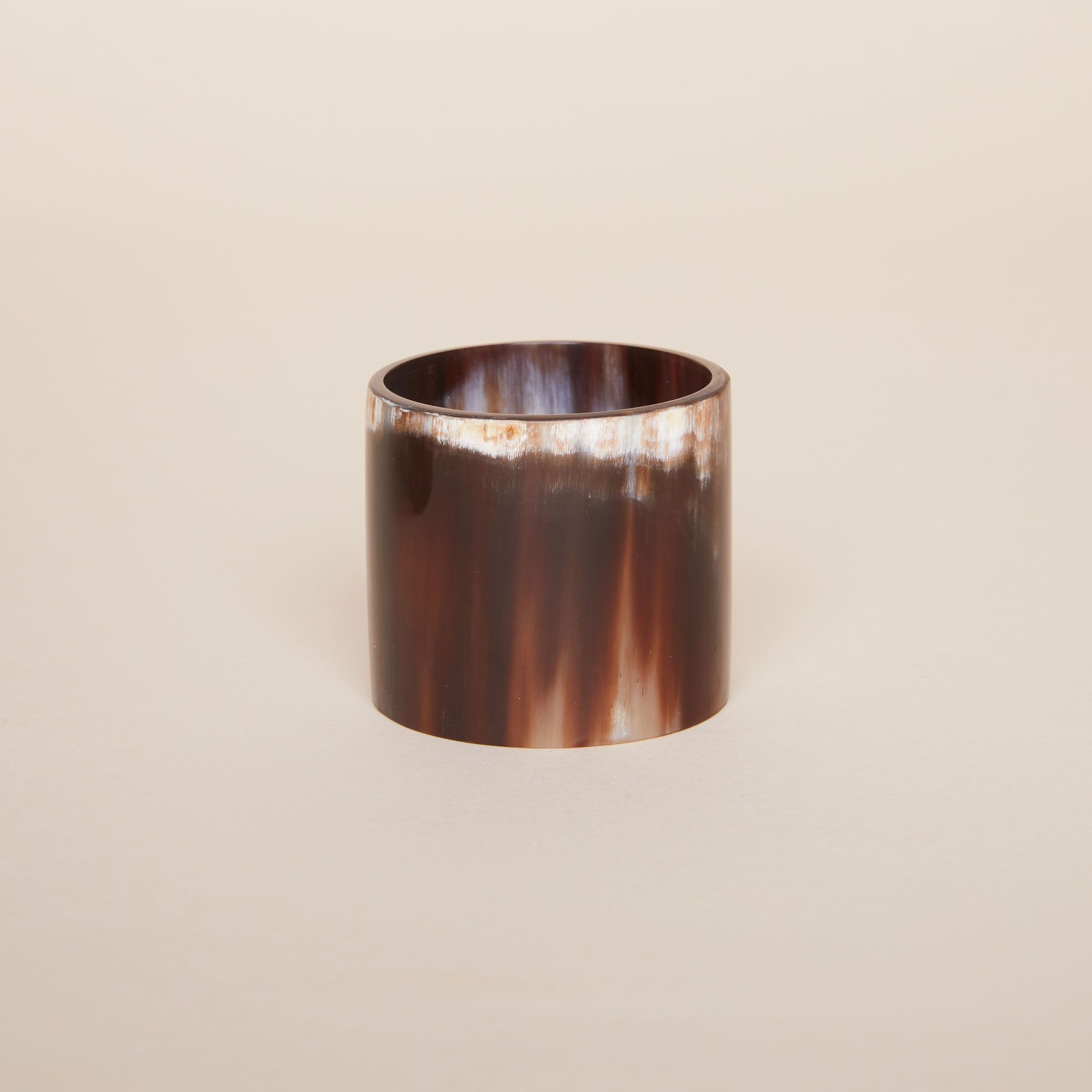 One cylindrical napkin ring, mostly dark brown with touches of white at top and bottom edges