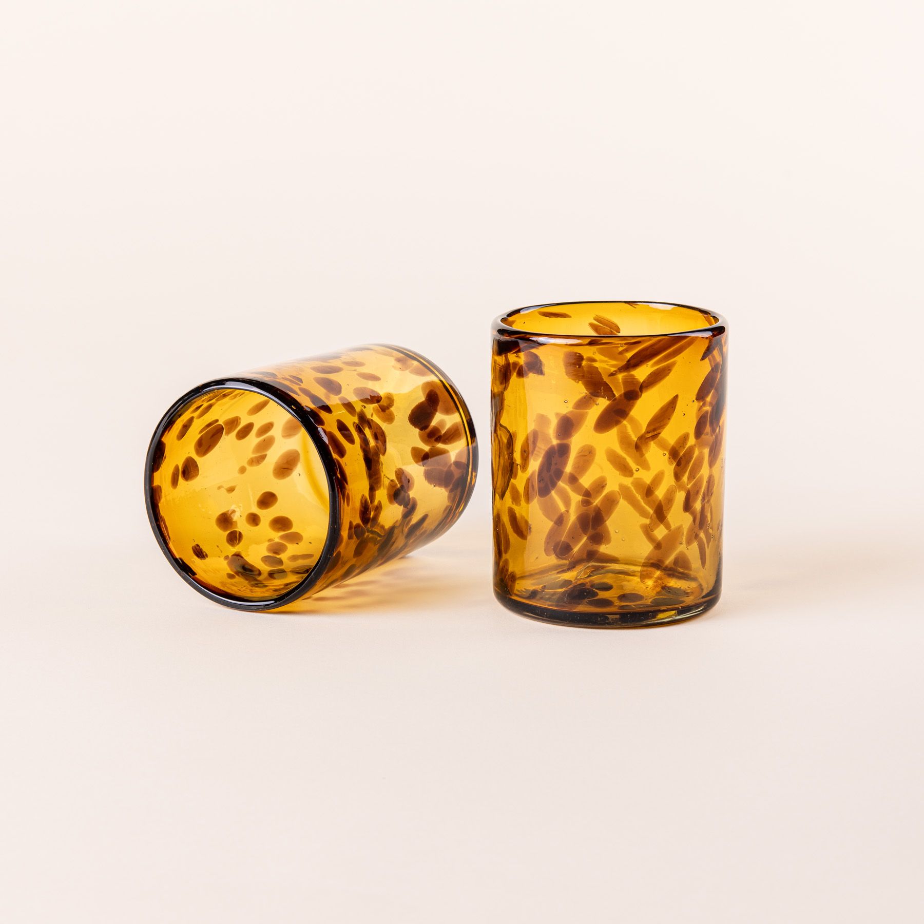 A short tortoiseshell drinking glass standing up and one on its side