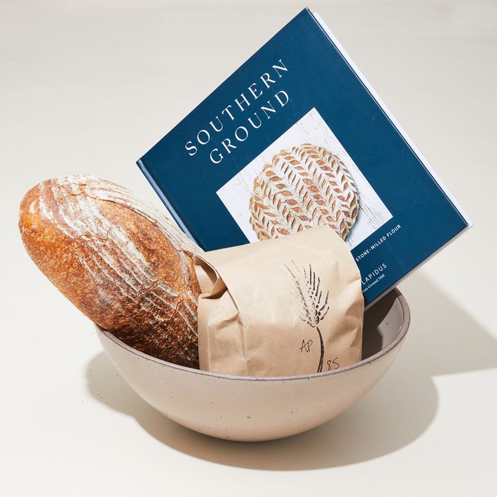 A panna cotta colored East Fork Mixing bowl filled with baking necessities (and fruits of labor): Southern Ground Cookbook, Flour and Bread Loaf