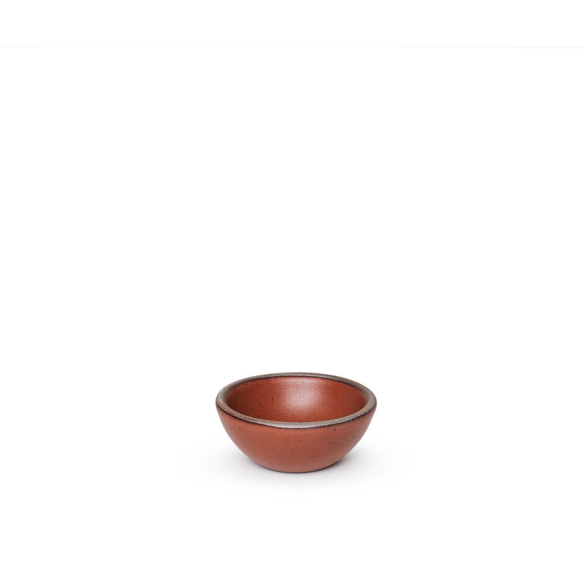 A tiny rounded ceramic bowl in a cool burnt terracotta color featuring iron speckles and an unglazed rim