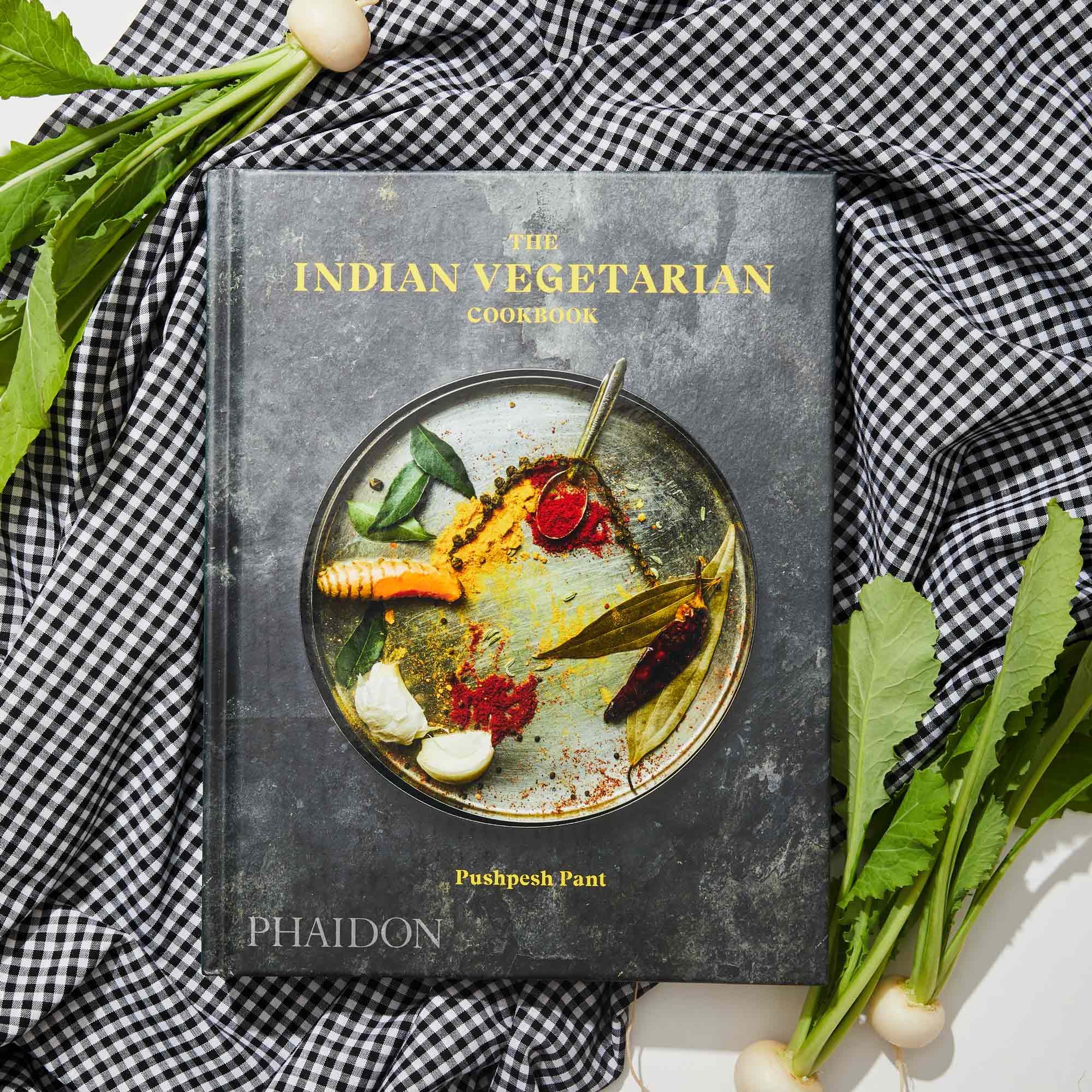 Black and white gingham fabric background, radishes with greens and copy of The Indian Vegetarian by Pushpesh Pant