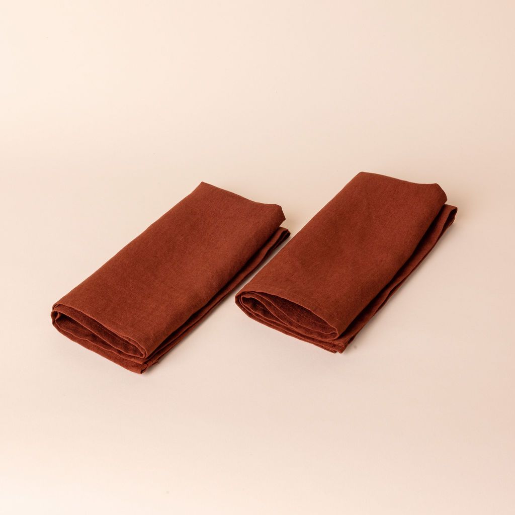Two terracotta linen napkins folded into rectangles side by side