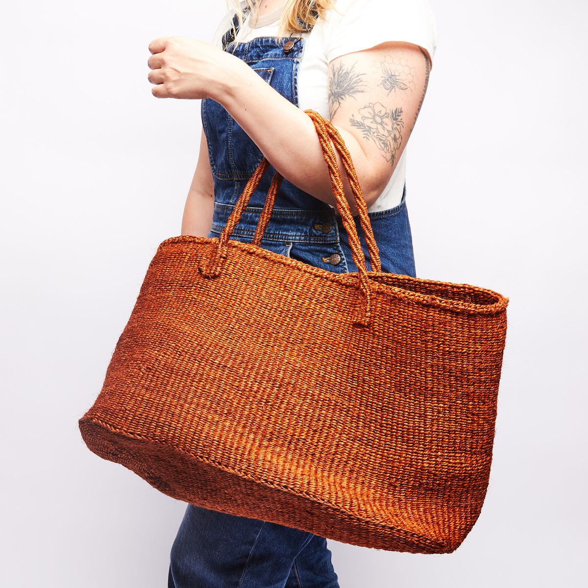 Person holding a large woven bag on their arm