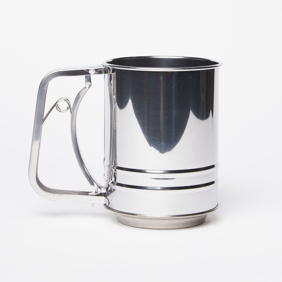 Shiny metal flour sifter with handle on the left on a white background