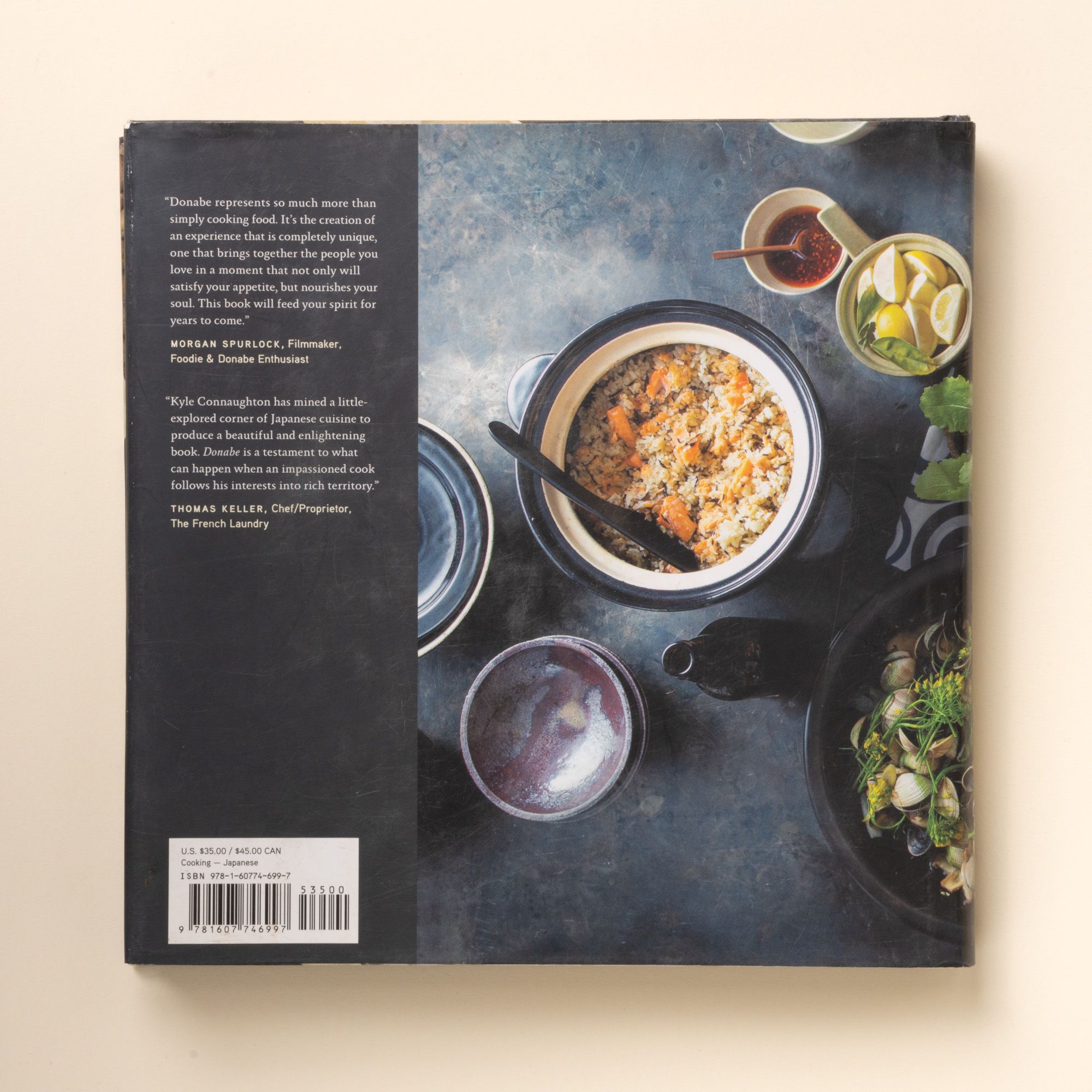Back cover of a donabe cookbook featuring a Japanese rice dish photo, small bowls, and printed reviews on a dark background.