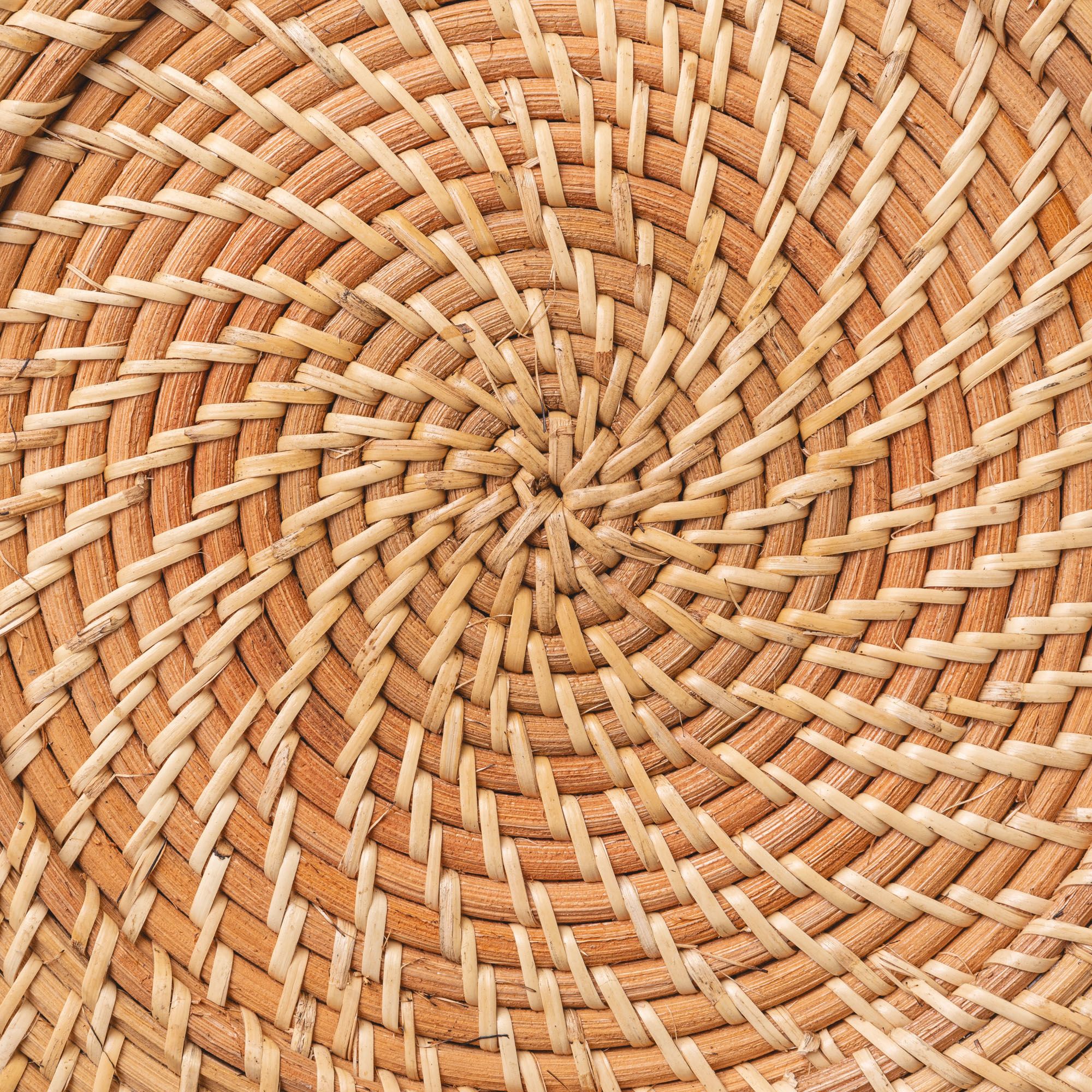 A close up of a natural hand woven dinner plate charger.