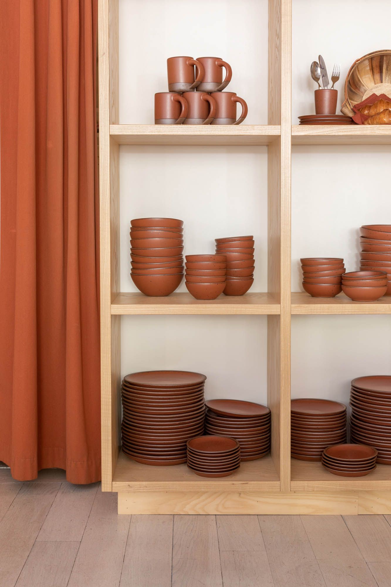 Wooden shelves showing off cool terracotta ceramic dinnerware
