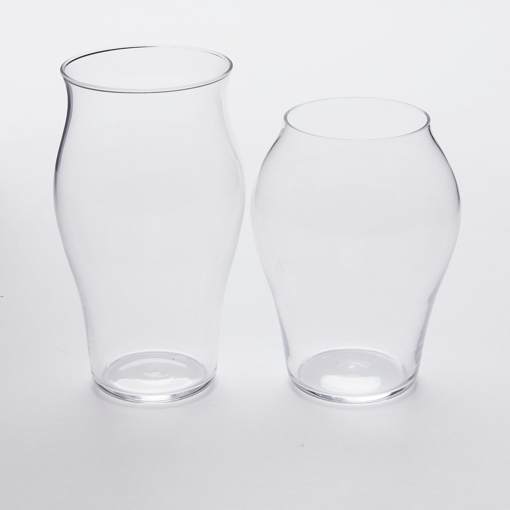 Two clear glasses, one taller than the other, both with curved bodies.