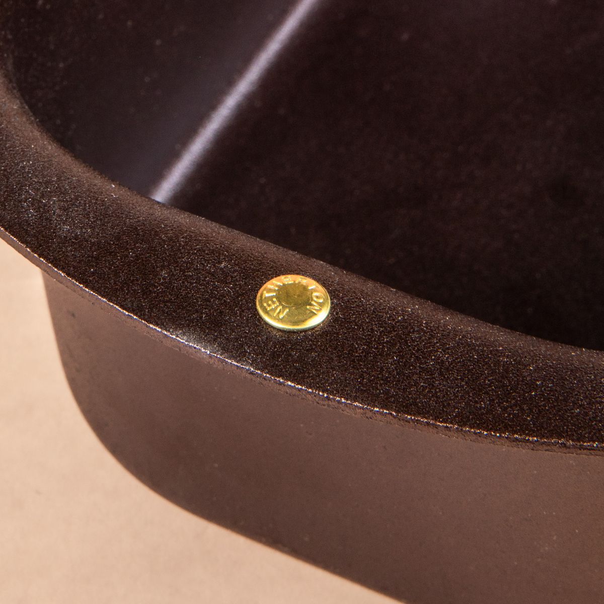 Close up of a gold branded screw on the edge of a black metal loaf pan