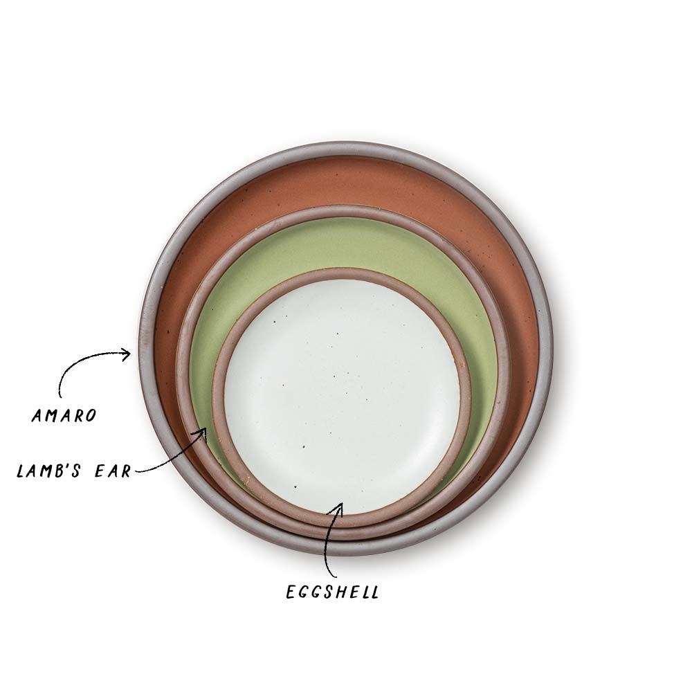 A stack of ceramic plates in a terracotta, calming sage green, and cool white colors.