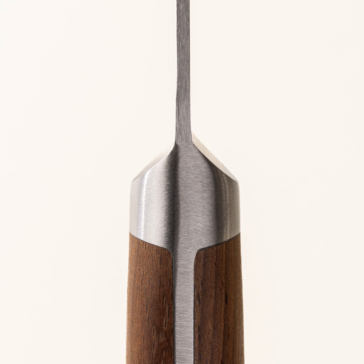 A close up of where the wooden handle meets the steel blade of a paring knife