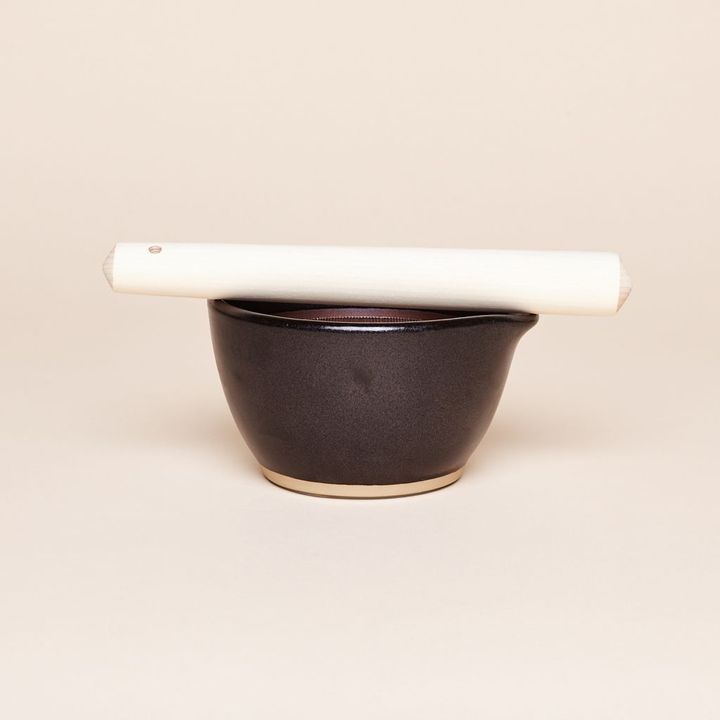 Black mortar with white pestle balanced across its top edge