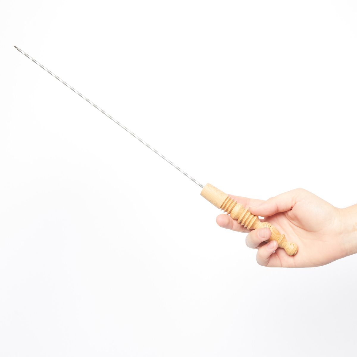 Hand holding a metal skewer with a wooden handle