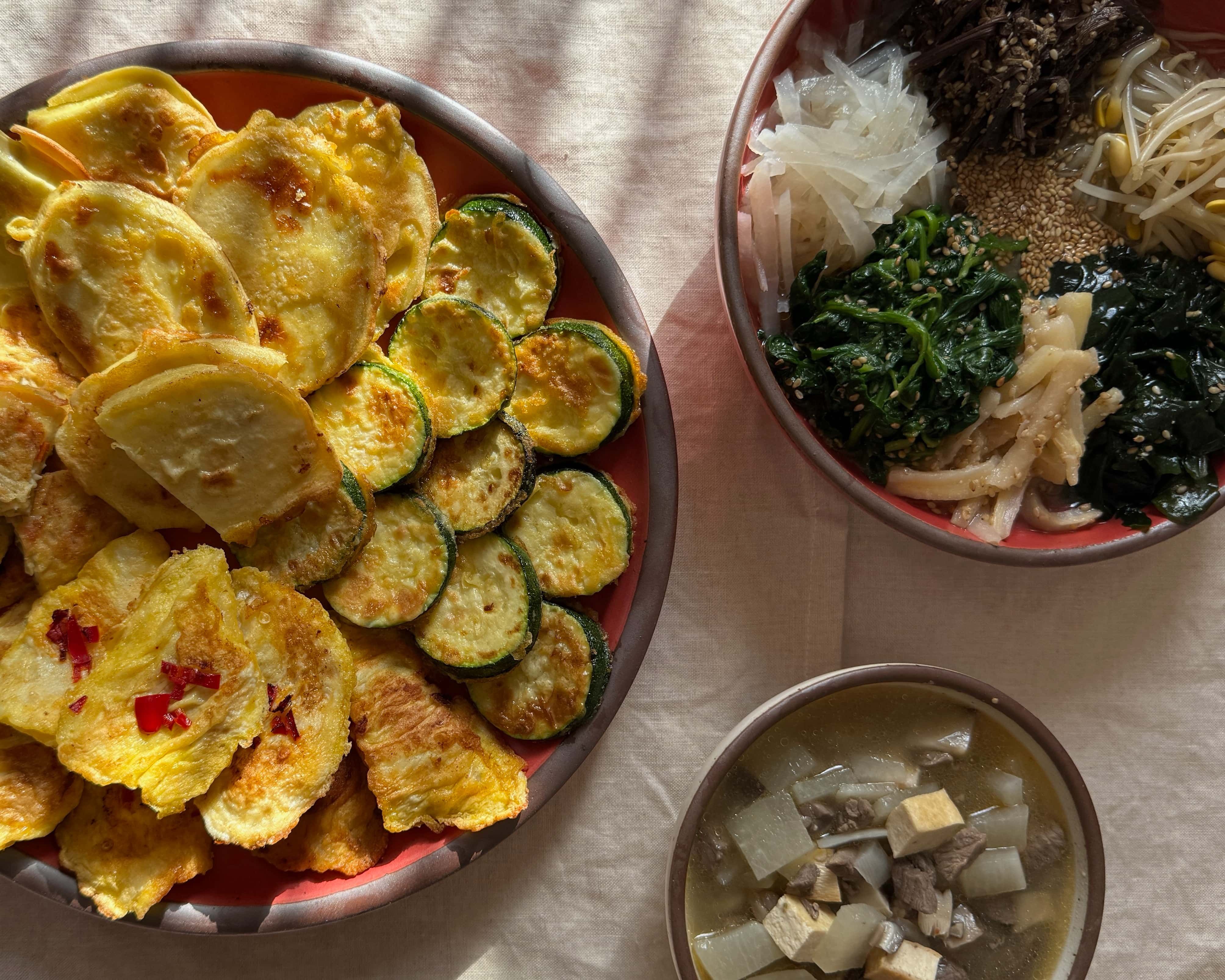 An overhead view of a Korean Lunar New Year spread of foods plated on ceramic plates and bowls