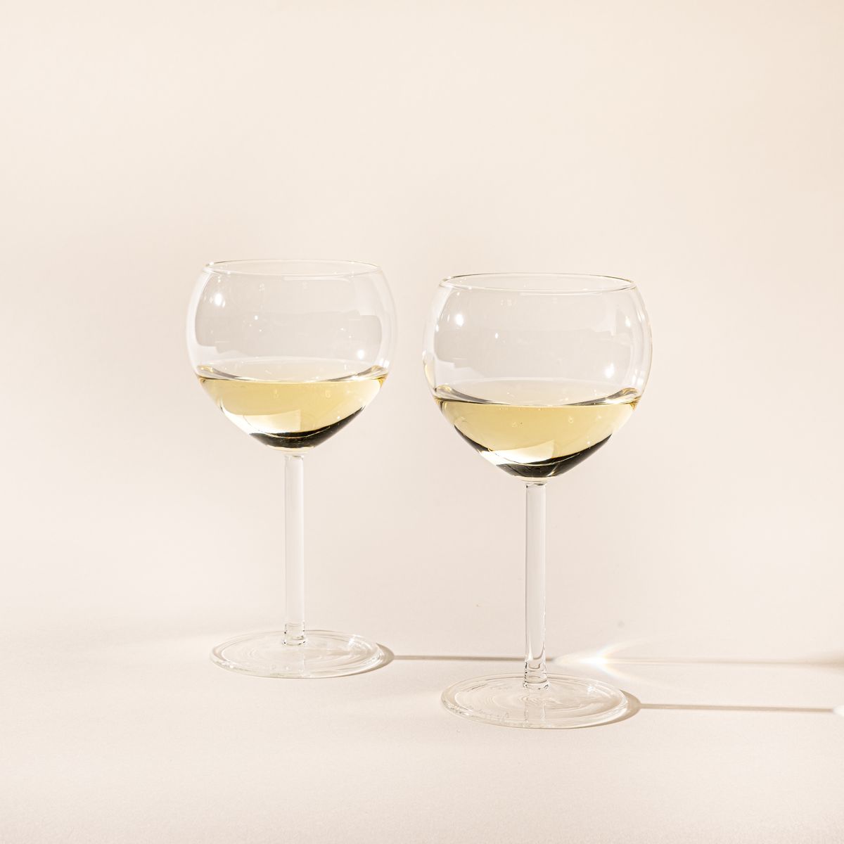 Two simple round clear wine glasses filled with white wine