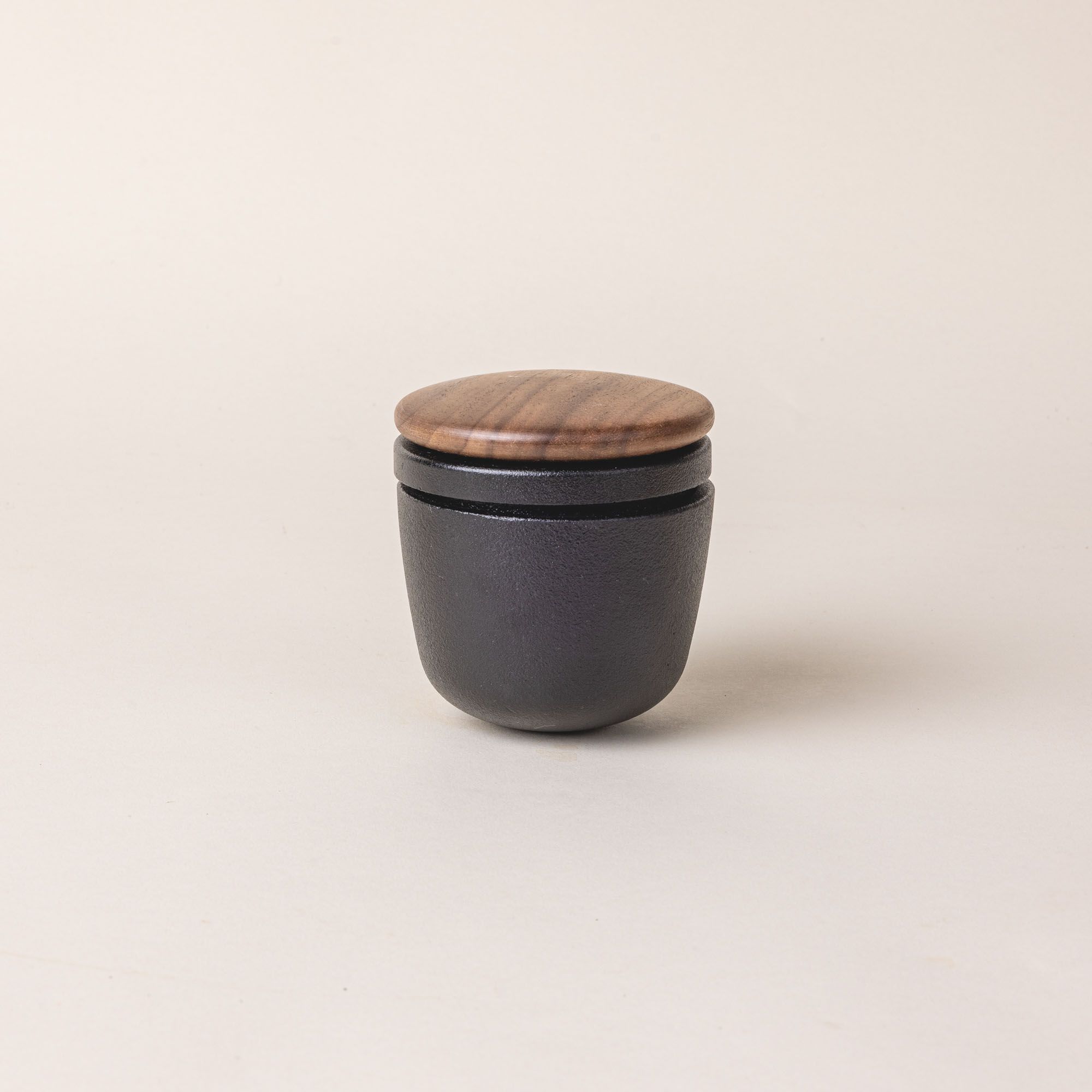 A short round cast iron jar with a wooden lid