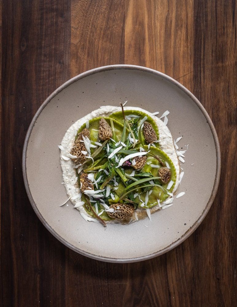 A beautiful and artful plate of green food on a couple plate in a pale warm brown color.