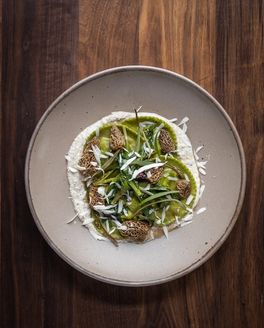 A beautiful and artful plate of green food on a couple plate in a pale warm brown color.