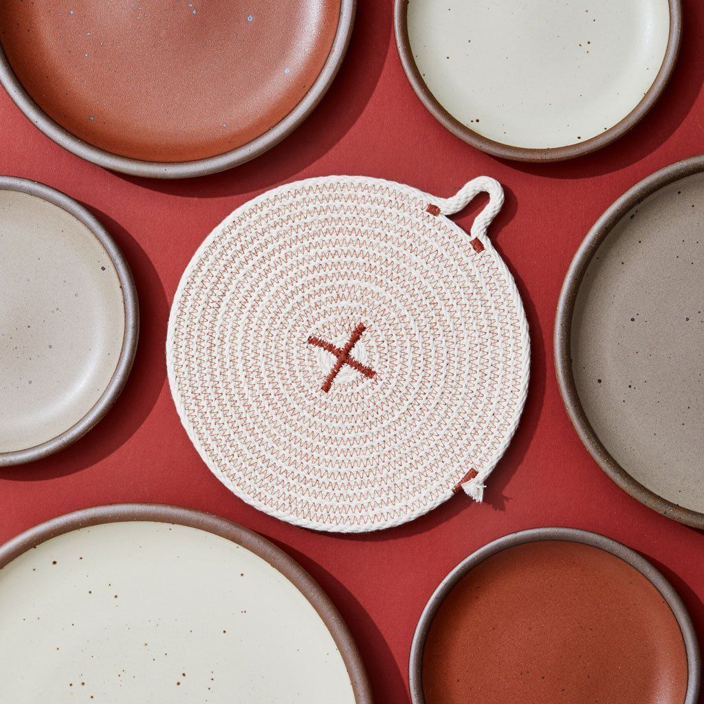 East Fork plates surround a trivet that is beige with Amaro thread