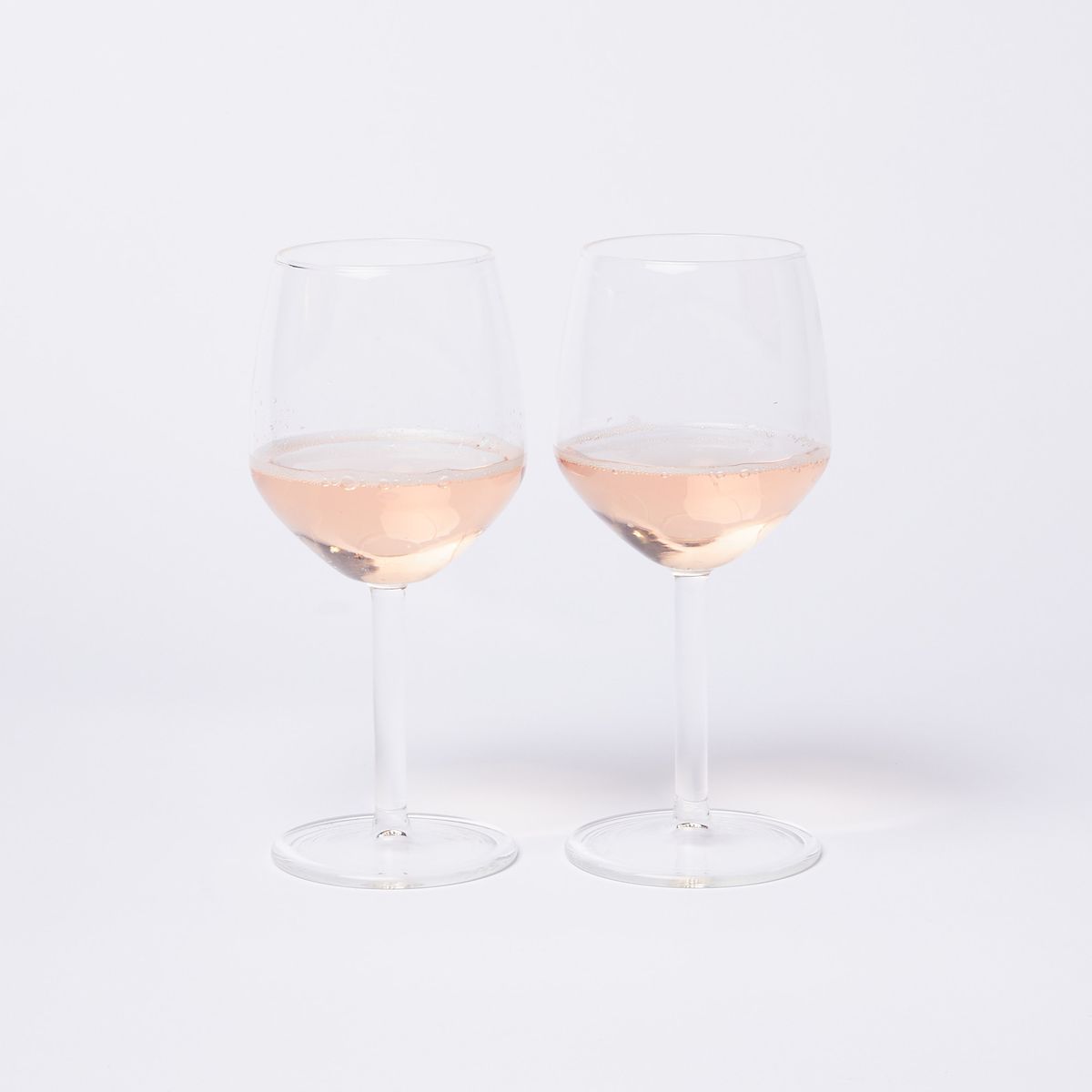 A pair of clear simple wine glasses with pink-tinted wine in each