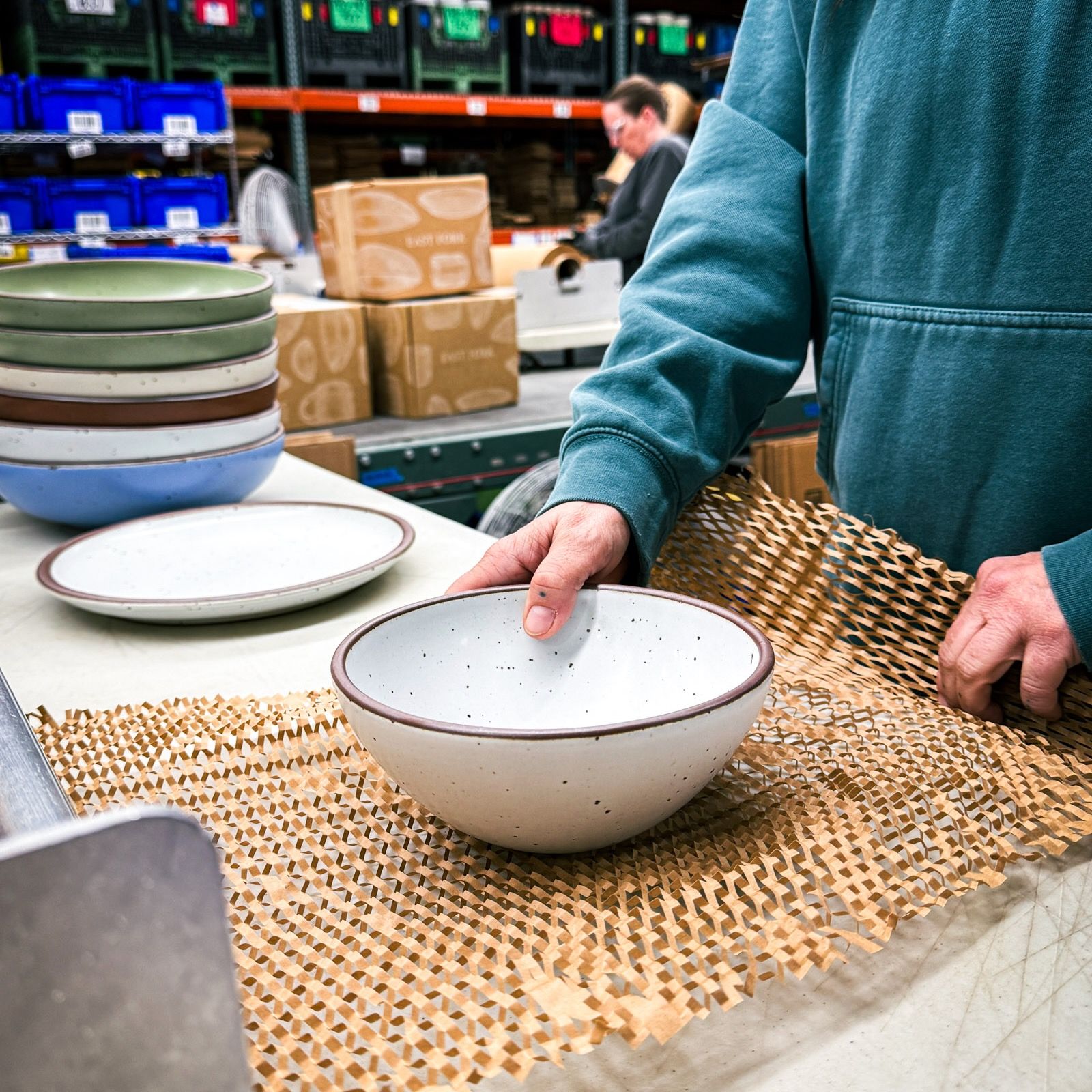 An overhead view of a table filled with several ceramic plates, an oval platter, wooden bowls, and a rectangular charcuterie board, along with silverware and wine glasses.