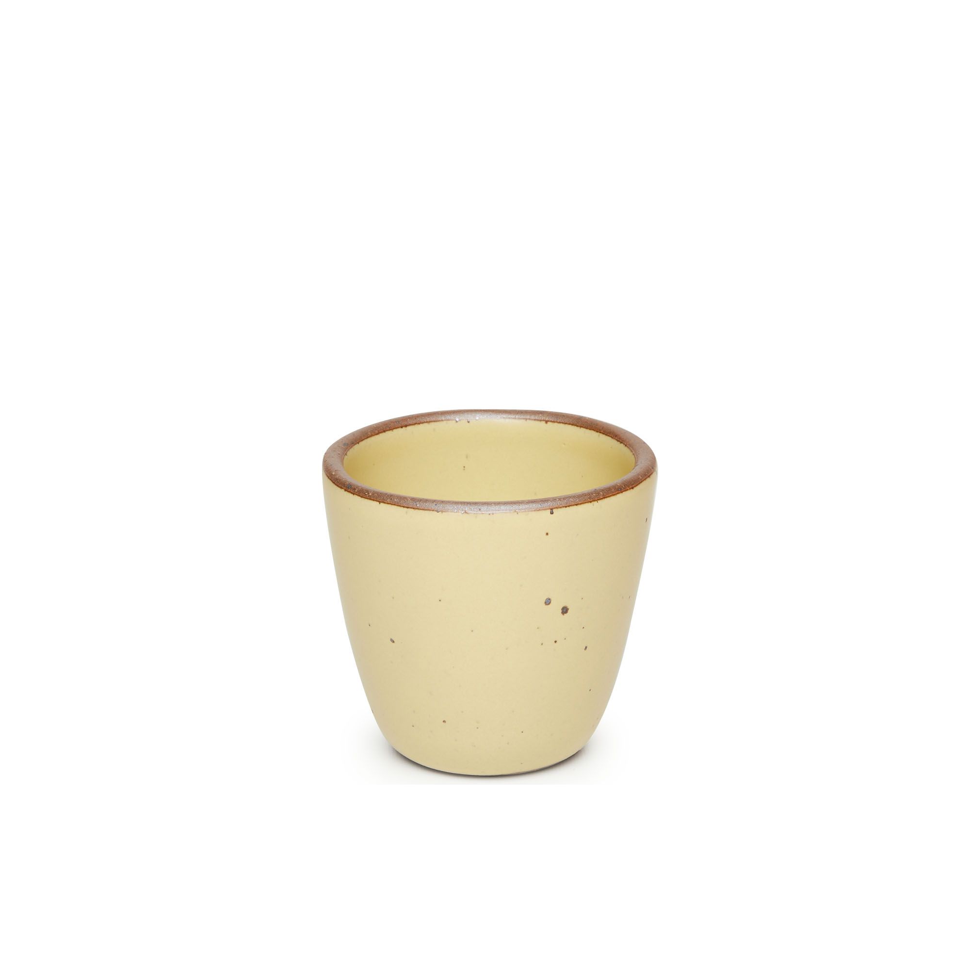 A short cup that tapers out to get wider at the top in a light butter yellow color featuring iron speckles