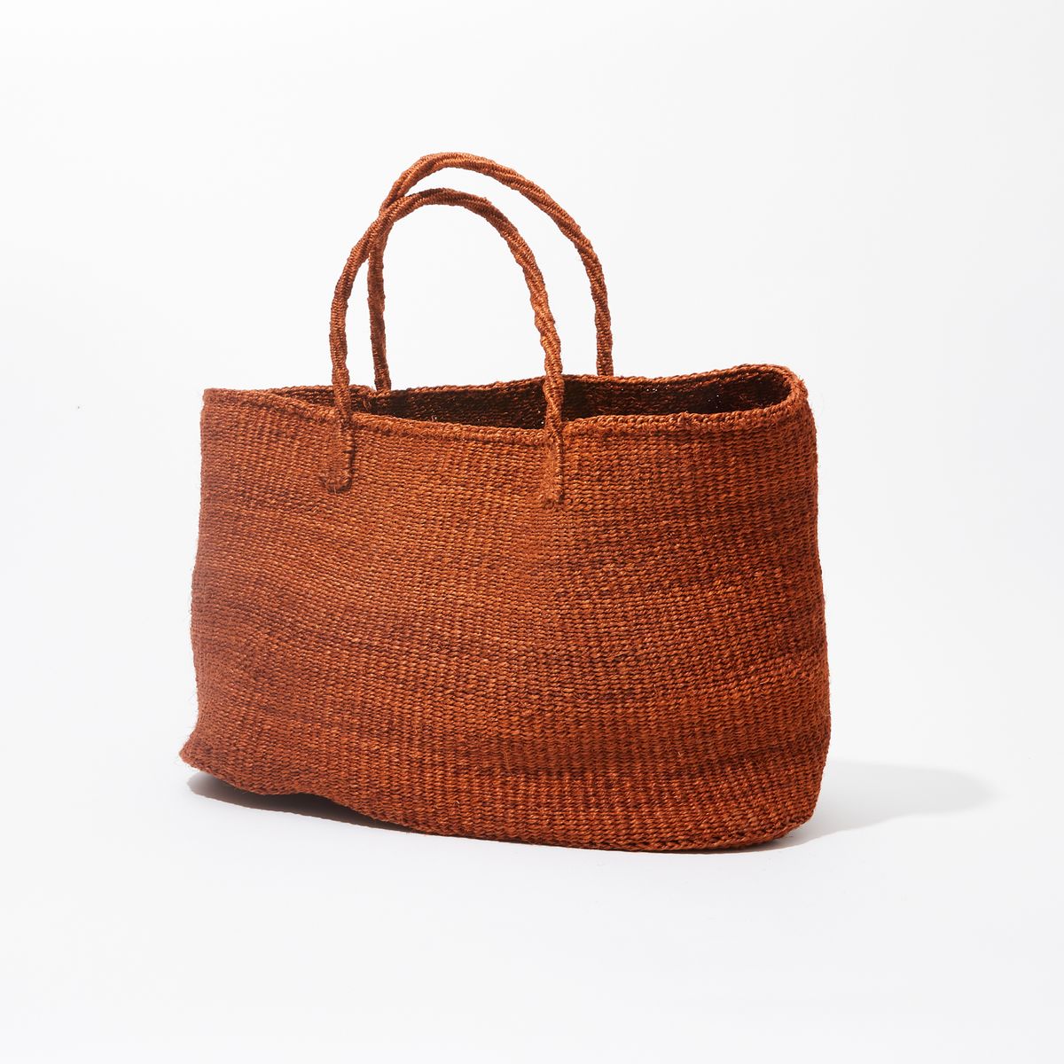 Large sisal woven bag with two handles resting on a white surface